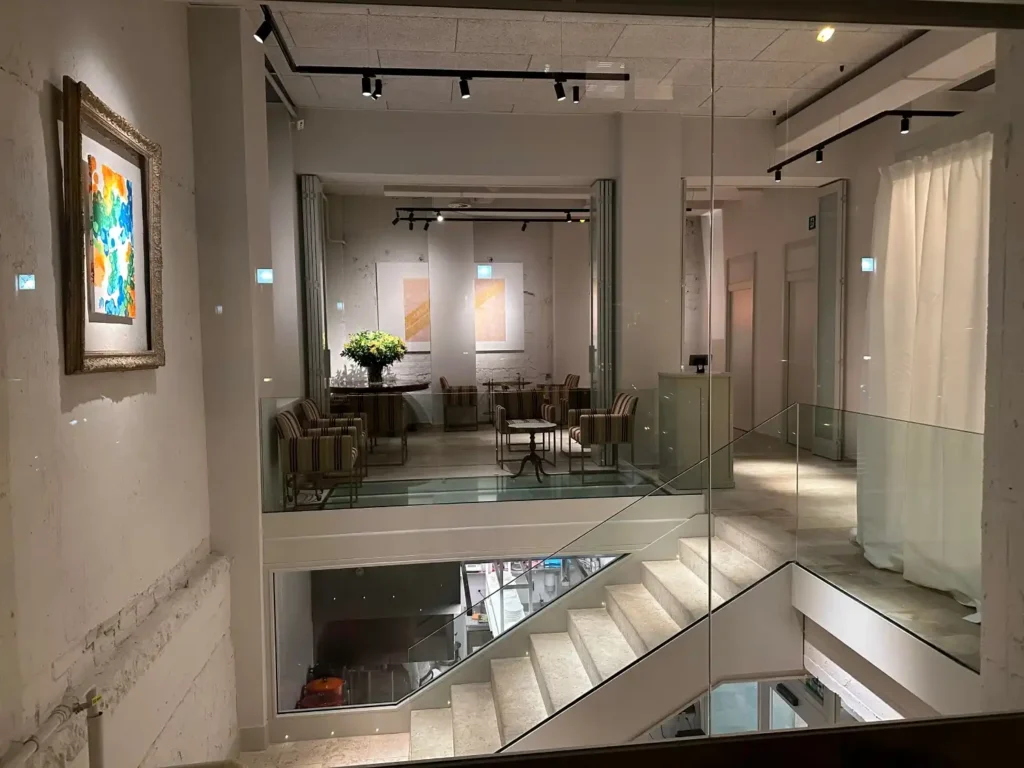 Muestra uno de los espacios del Restaurante Pabu, en este caso se ve una escalera de marmol y en la planta superior espacios diafanos con mesas y sillas